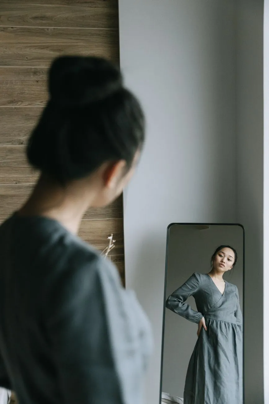 Cô gái mặc váy xám ngắm mình trong gương