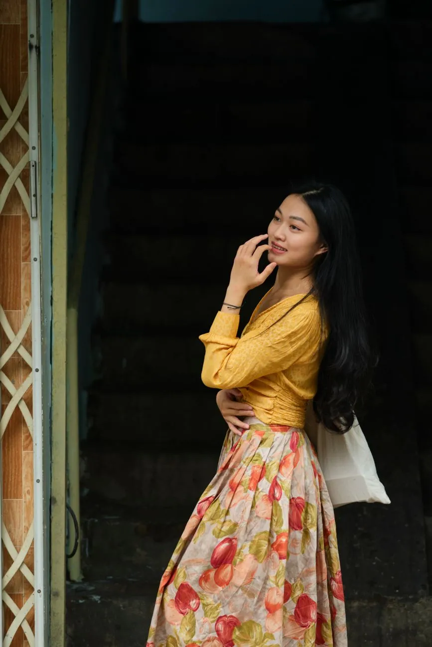 Cô gái mặc áo vàng sáng màu và chân váy hoa xoè dài