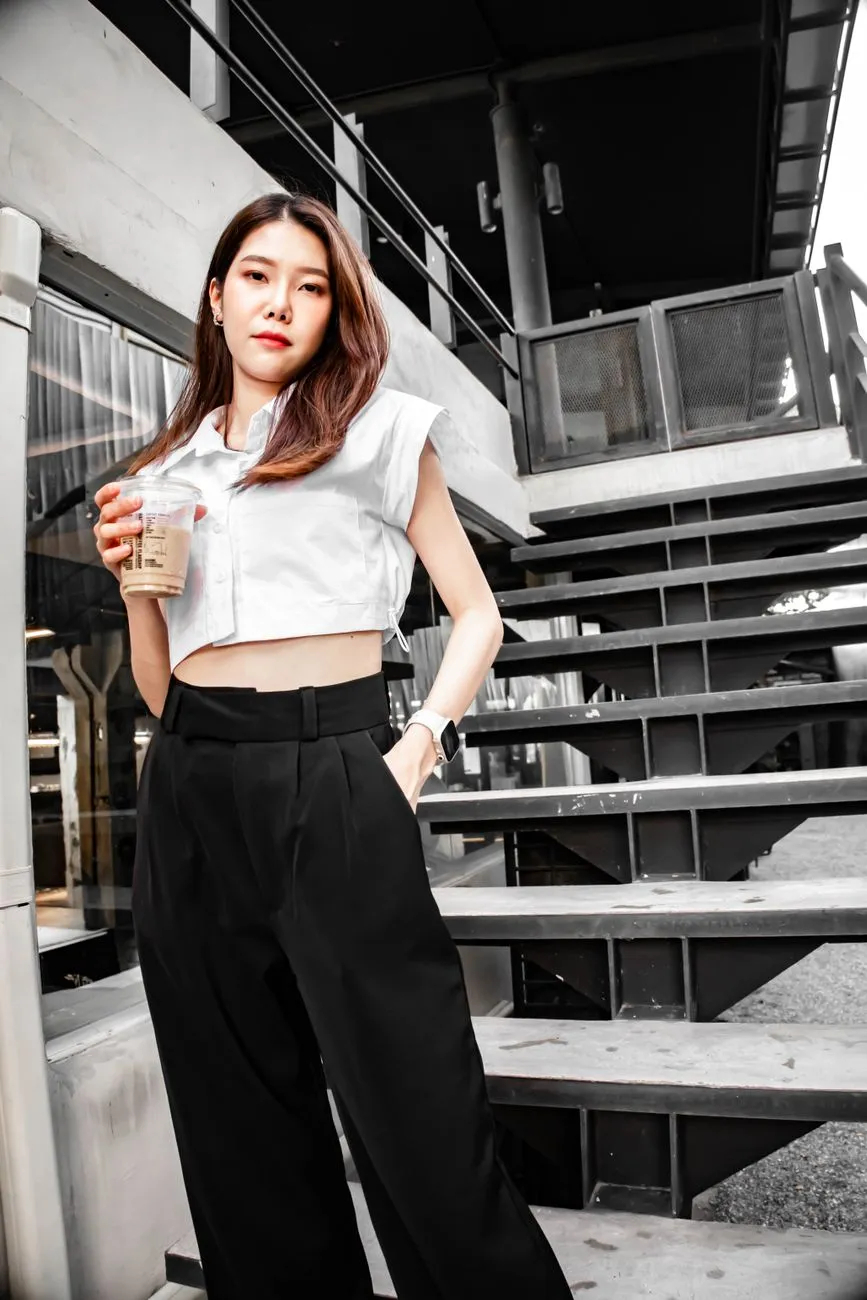 Cô gái mặc áo croptop trắng và quần ống rộng lưng cao màu đen
