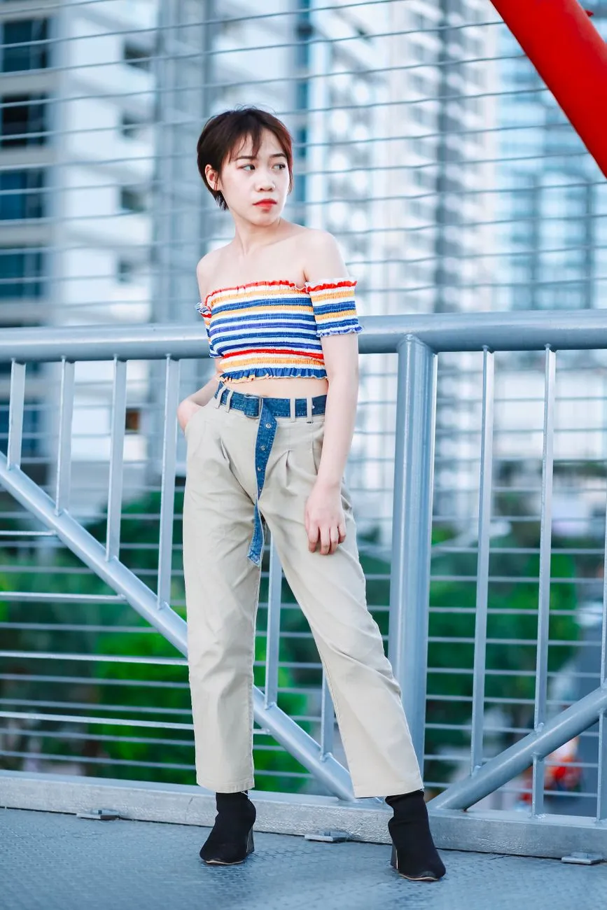 Cô gái mặc áo kẻ ngang trễ vai và quần ống suông lưng cao màu be