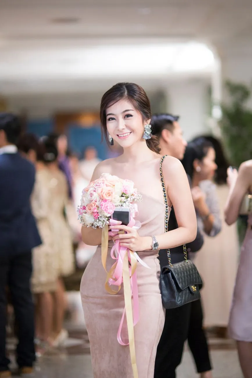 Cô gái mặc váy hồng nhạt dáng dài, cầm bó hoa tại tiệc cưới