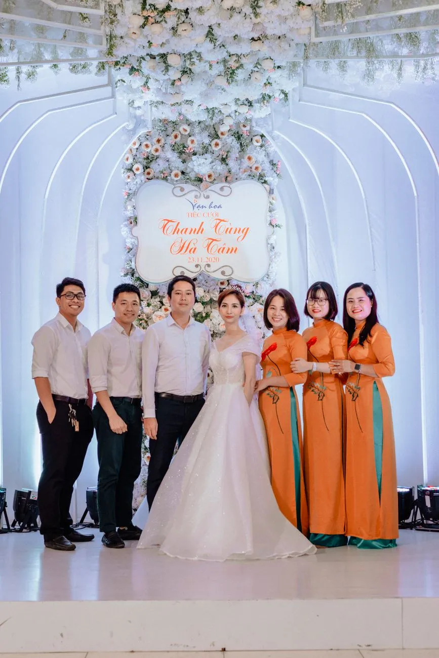 Cô dâu chú rể cùng người thân trong tiệc cưới Việt Nam, nam mặc sơ mi trắng, nữ mặc áo dài